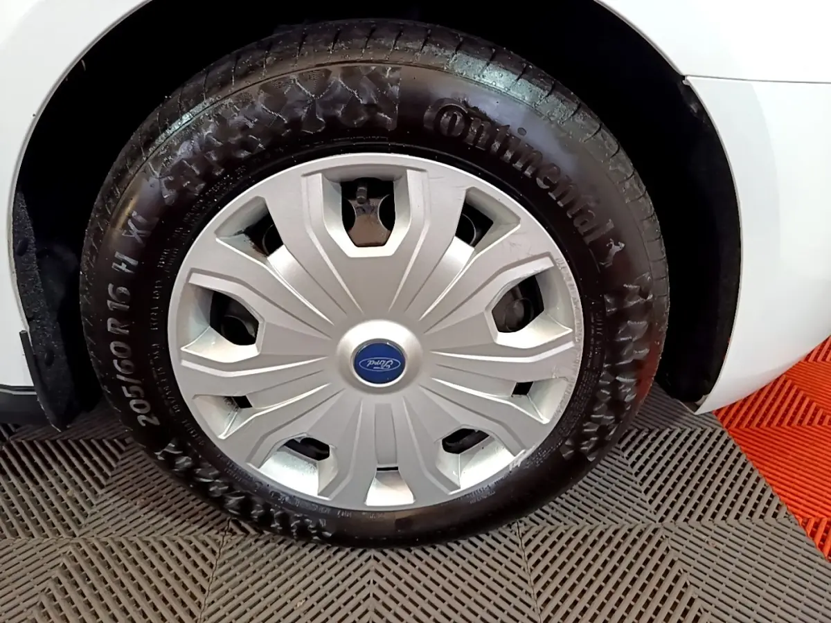 Gros plan sur la roue avant droite d’un Ford Transit Fourgon blanc avec enjoliveur argenté et pneu Continental.