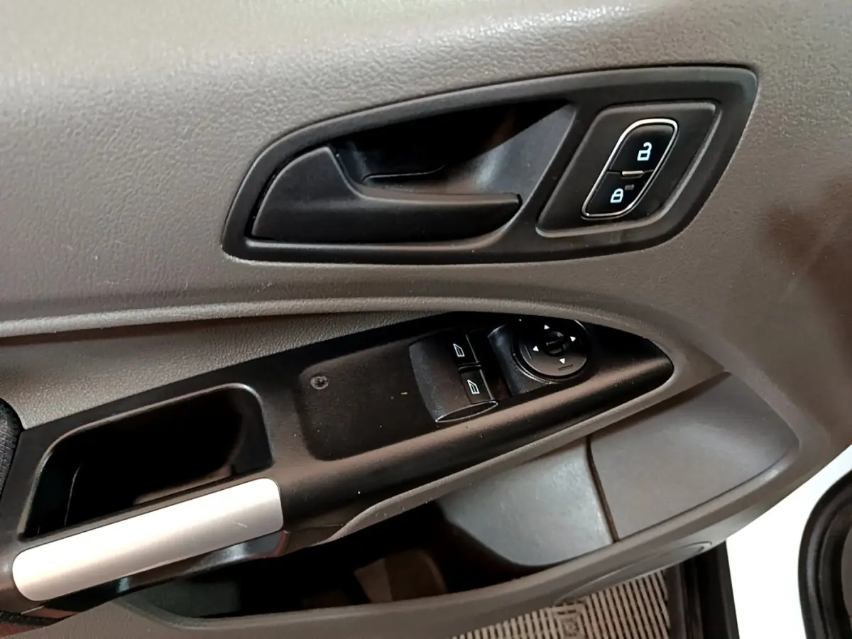 Gros plan sur la poignée intérieure et les commandes de vitres côté conducteur du Ford Transit Fourgon blanc, version 2022.