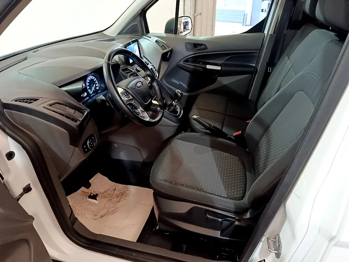 Vue intérieure côté conducteur du Ford Transit Fourgon blanc 2022, montrant le tableau de bord et les sièges avant noirs.