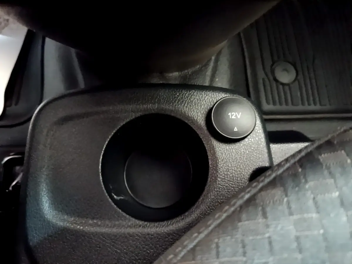 Gros plan sur la prise 12V et porte-gobelet noir dans l’habitacle du Ford Transit Fourgon blanc, côté conducteur.