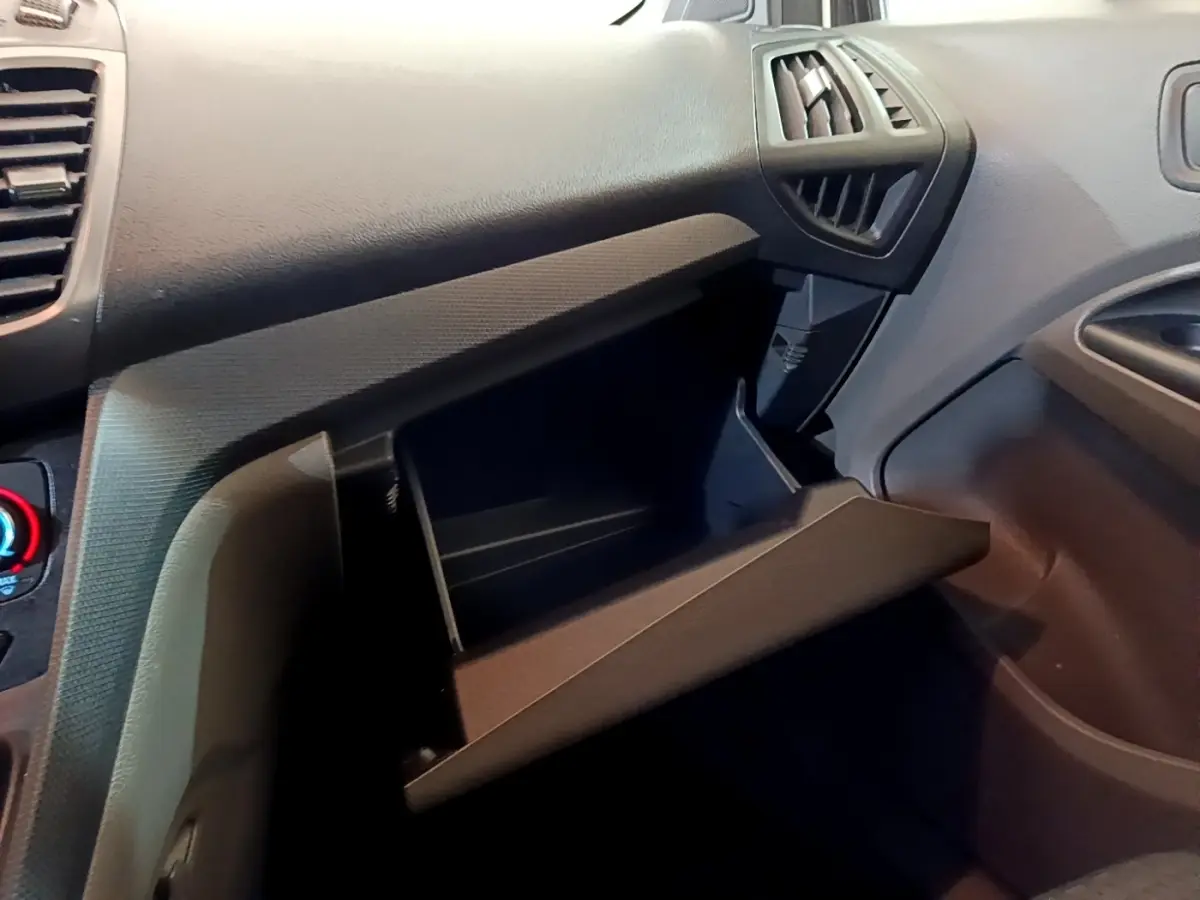 Vue intérieure du tableau de bord côté passager du Ford Transit Fourgon 2022 avec boîte à gants ouverte en plastique noir.