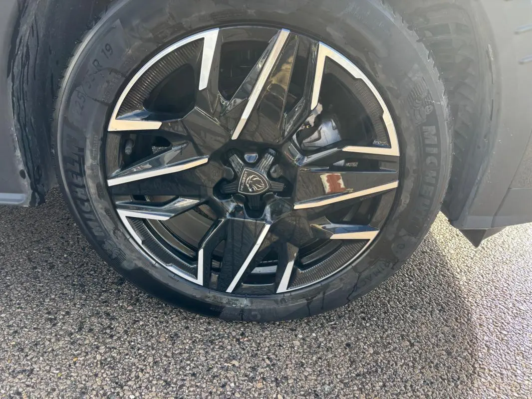 Gros plan sur la jante alliage noire et argentée de 19 pouces du Peugeot 3008 Hybrid gris, avec pneu Michelin visible.