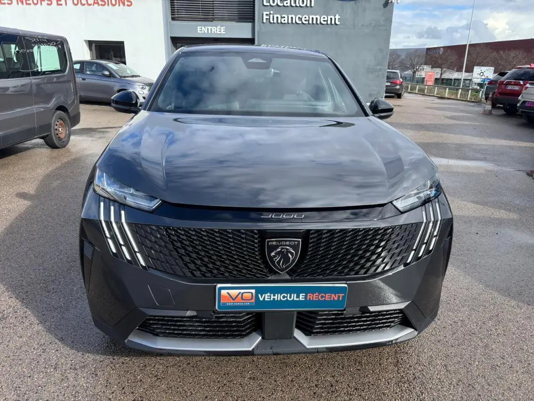 Vue de face du Peugeot 3008 Hybrid gris 2025 avec calandre noire et feux LED verticaux allumés.
