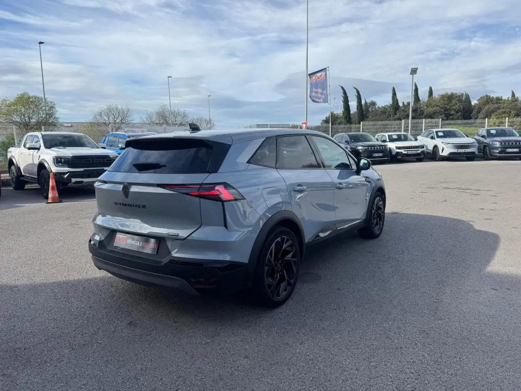 Renault Symbioz gris clair vu en 3/4 arrière droit, avec jantes alliage noires et antenne requin.