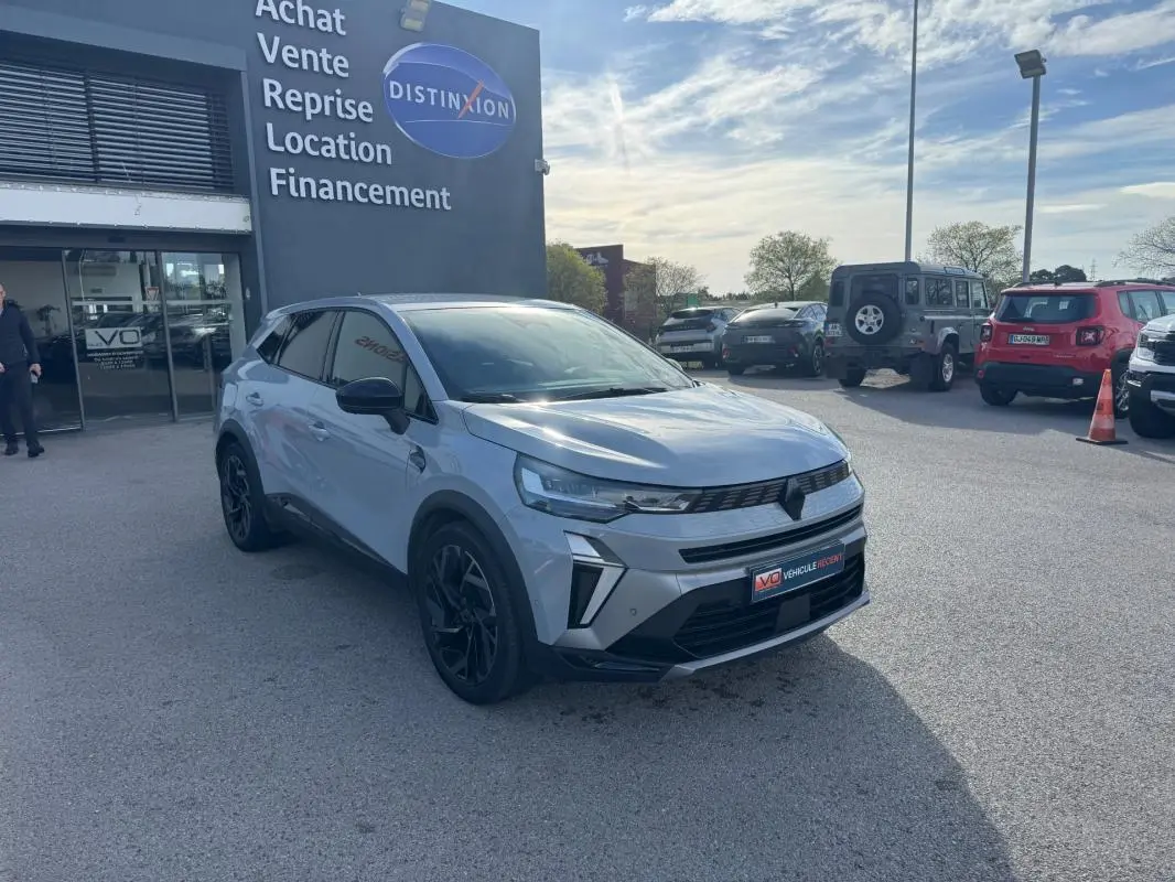 Renault Symbioz gris clair en 3/4 avant droit, jantes alliage noires et calandre moderne visible en extérieur.