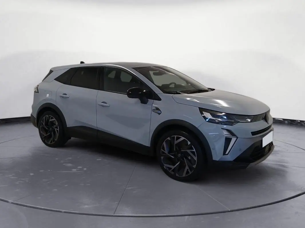 Renault Symbioz gris clair en 3/4 avant droit, avec jantes alliage noires et toit noir contrasté.