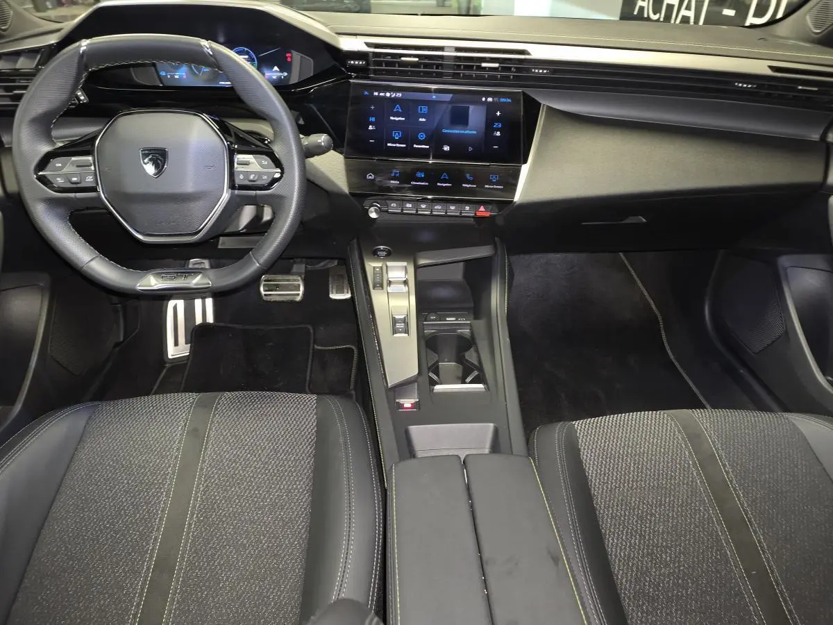 Vue intérieure avant de la Peugeot 408 GT 2025, tableau de bord noir avec écran tactile 10 pouces et volant cuir perforé.