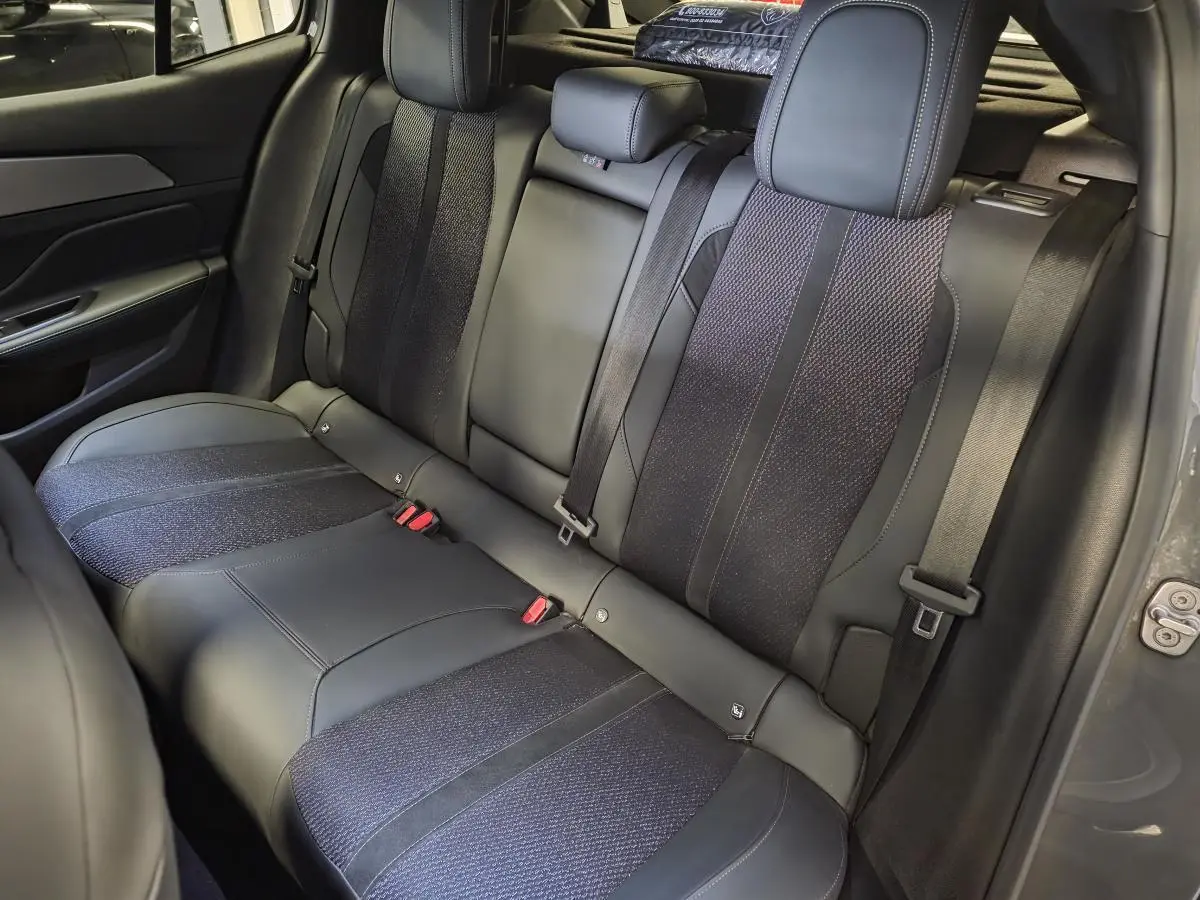 Vue intérieure de la banquette arrière en tissu et cuir noir de la Peugeot 408 gris Selenium, avec ceintures de sécurité visibles.
