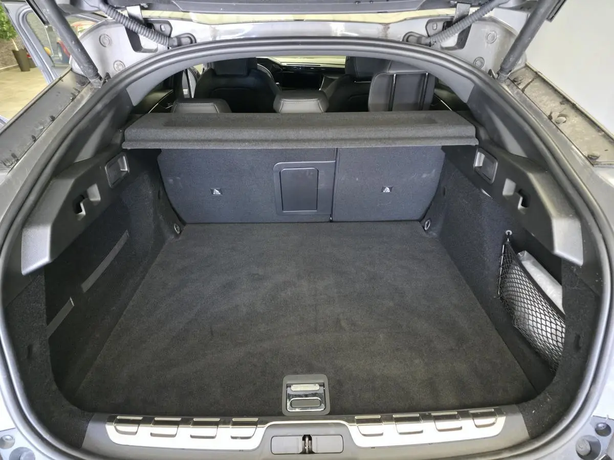 Coffre ouvert vu de l'arrière d'une Peugeot 408 gris, montrant un espace de chargement propre et bien agencé.