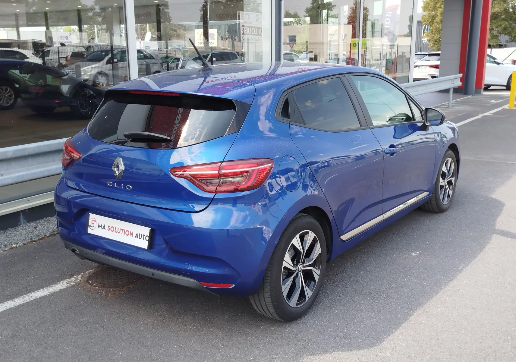 Vue 3/4 arrière droite d'une Renault Clio 1.0 SCe 65ch Evolution bleu Iron avec jantes alliage et vitres teintées.
