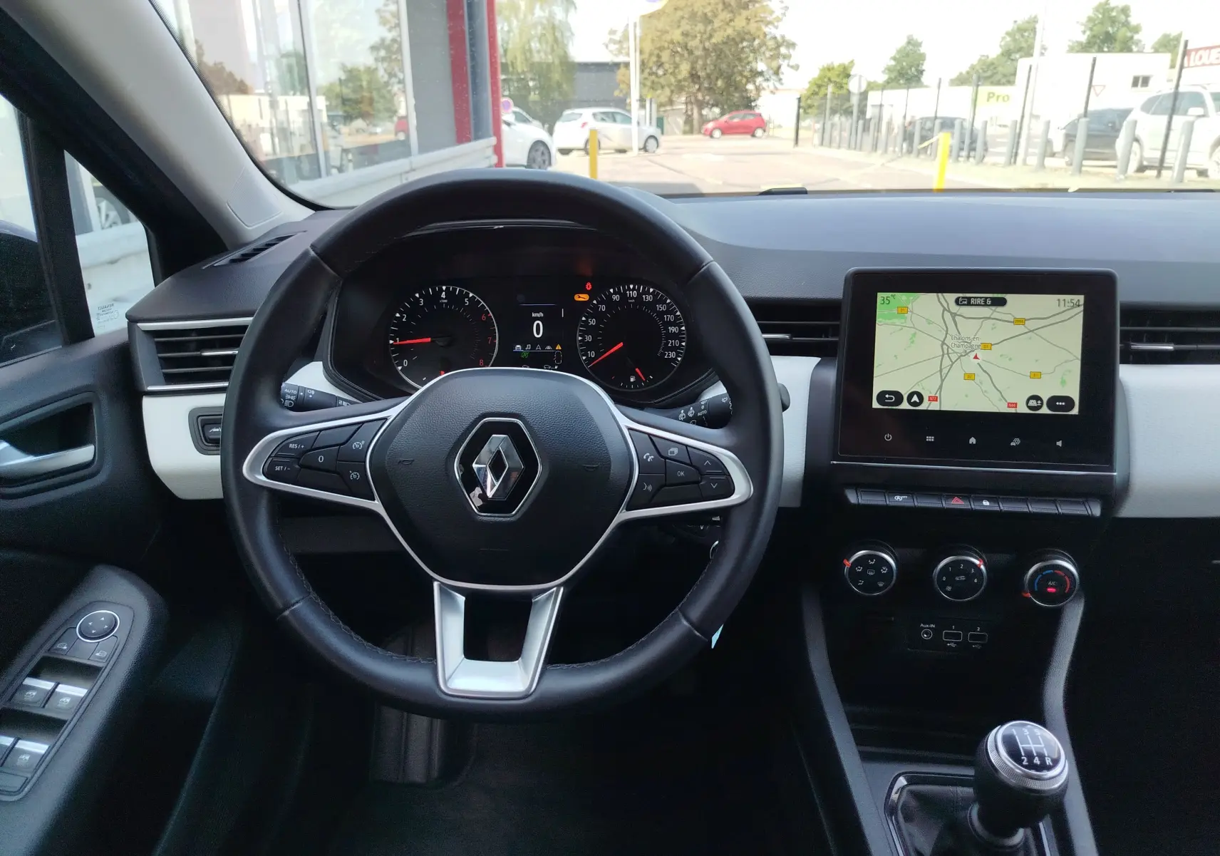 Vue intérieure frontale du poste de conduite de la Renault Clio Bleu Iron 2022 avec volant multifonction et écran tactile central.