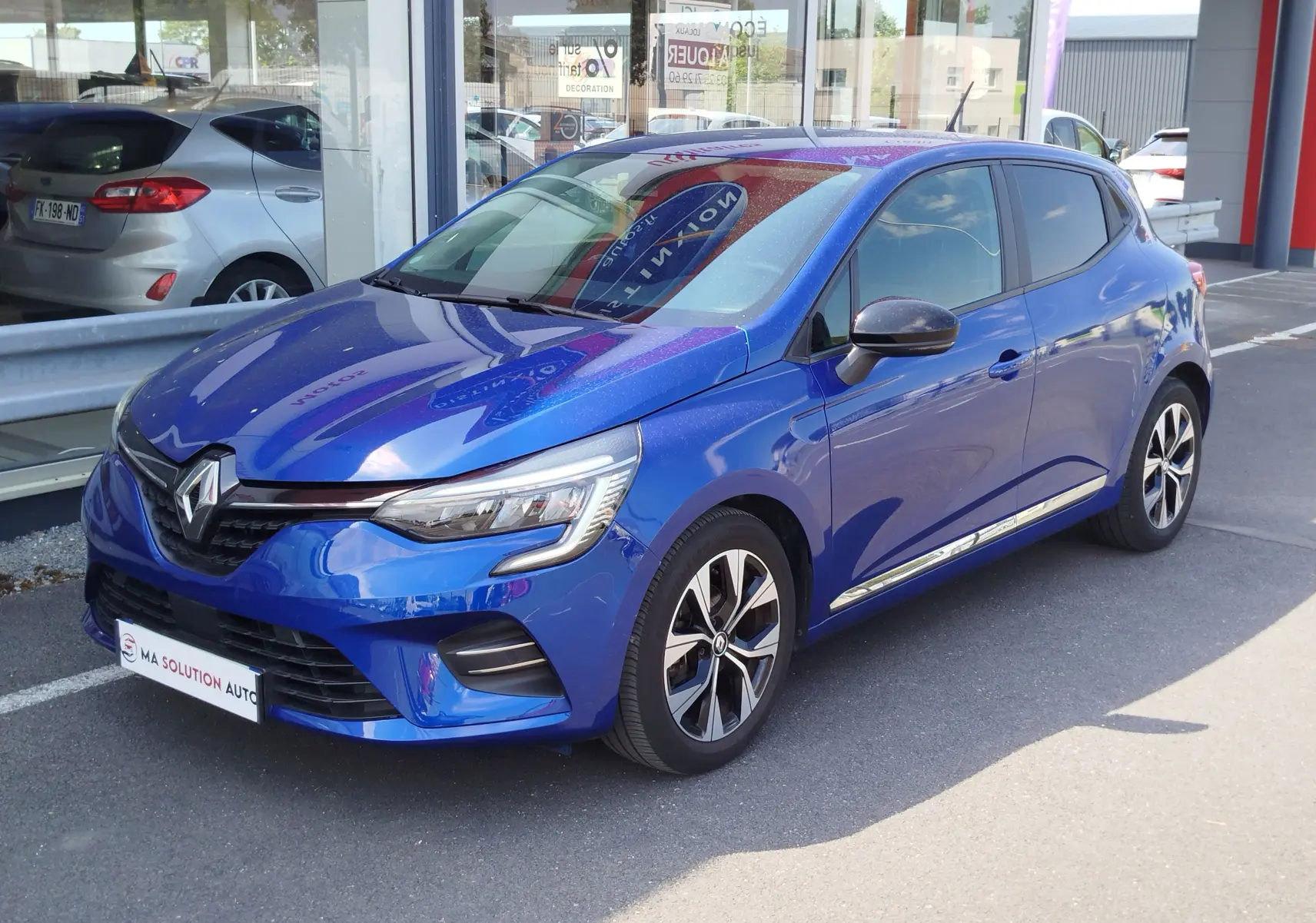 Renault Clio 1.0 SCe 65ch Evolution bleu Iron vue 3/4 avant droit, avec jantes alliage et phares LED distinctifs.