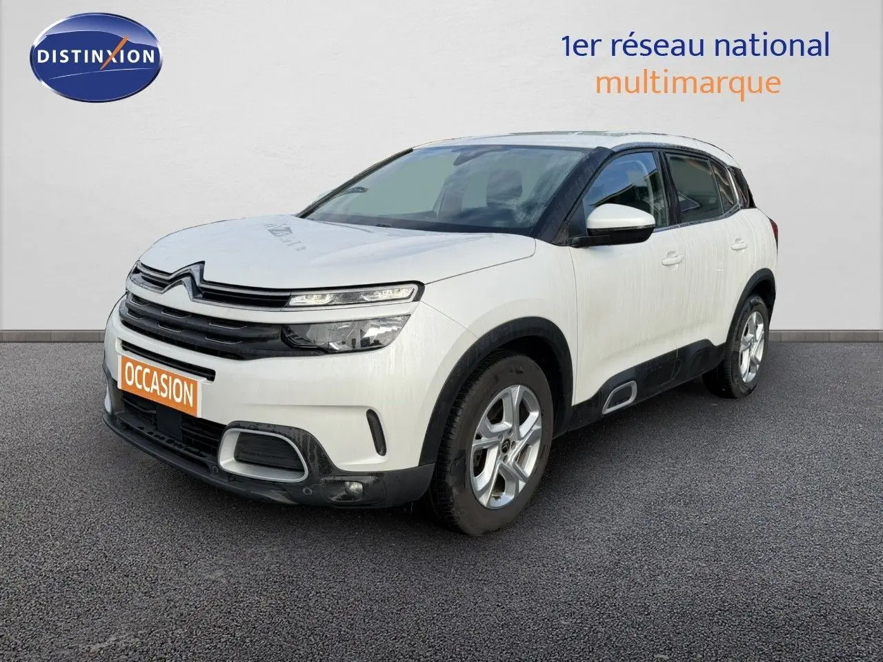Vue 3/4 avant d'un Citroën C5 Aircross blanc nacré avec détails noirs et jantes argentées sur fond neutre.