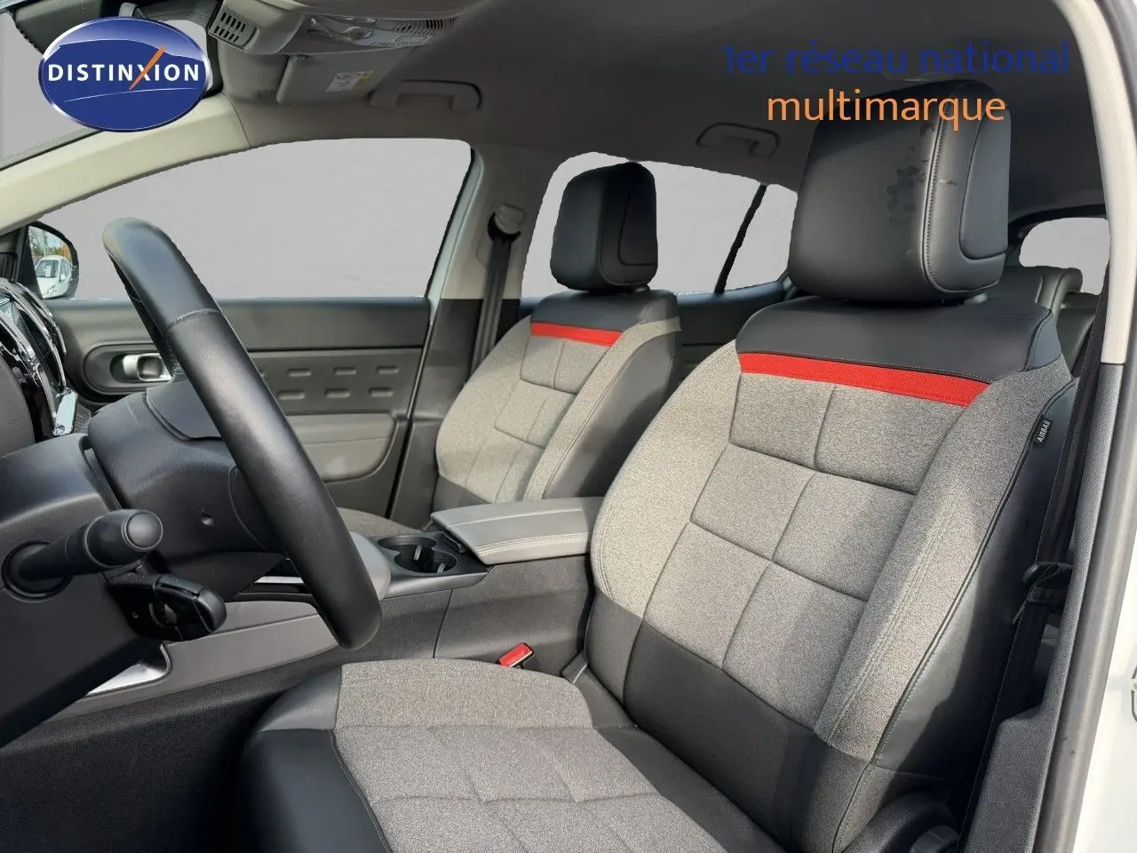 Vue intérieure côté conducteur du Citroën C5 Aircross blanc nacré, sièges gris avec bande rouge et cuir noir.