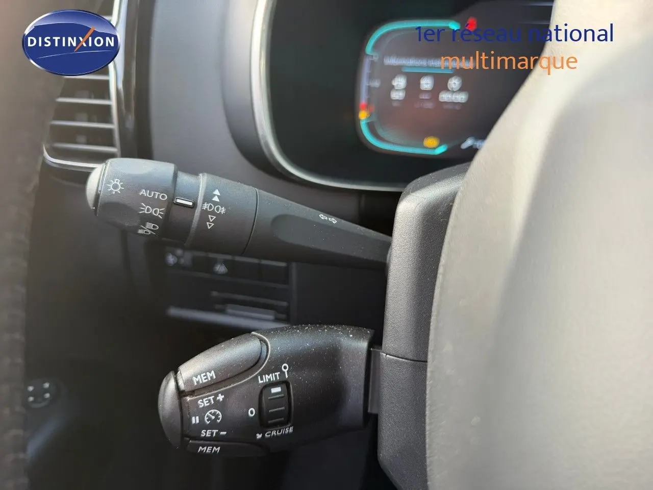 Gros plan sur les commandes au volant du Citroën C5 Aircross blanc nacré, mettant en valeur les réglages de vitesse et phares.