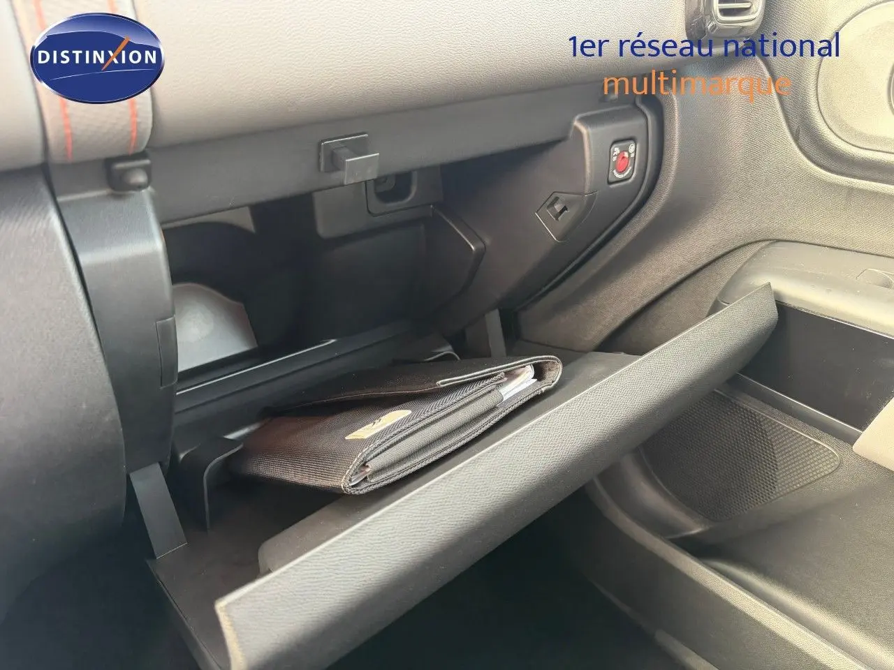 Gros plan de la boîte à gants ouverte côté passager du Citroën C5 Aircross blanc nacré avec un porte-documents noir à l'intérieur.