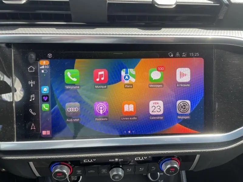 Écran tactile central de l'Audi Q3 blanc 2021 affichant les applications Apple CarPlay avec commandes climatisation en dessous.