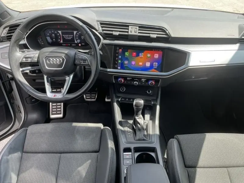 Intérieur Audi Q3 35 TFSI 2021 vu de face, tableau de bord moderne avec écran tactile et volant sport S-Line.