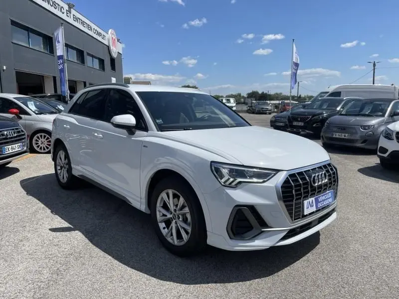 Audi Q3 blanc en vue 3/4 avant droit, avec calandre S-Line distinctive et jantes alliage, stationné en extérieur.
