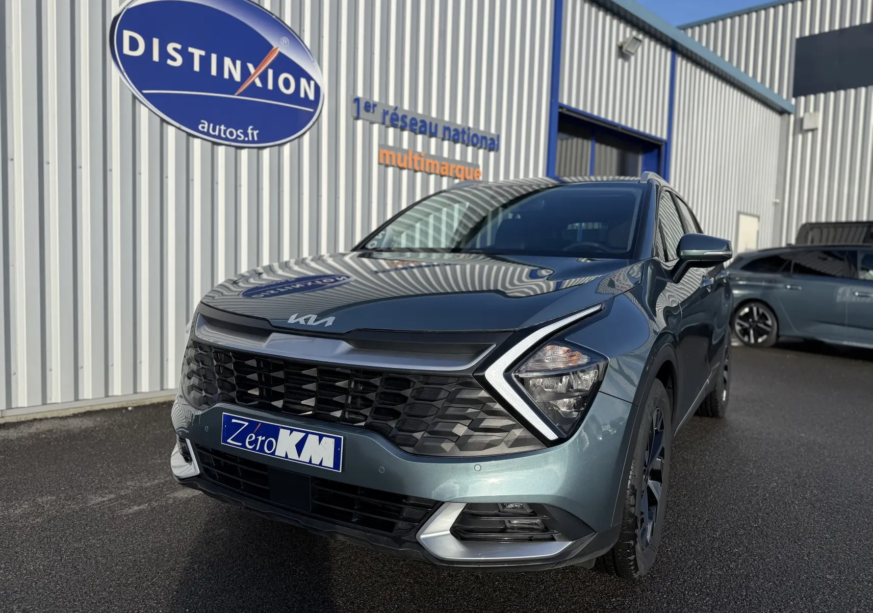 KIA SPORTAGE gris Sirius en 3/4 avant droit, avec calandre noire et jantes alliage bicolores.