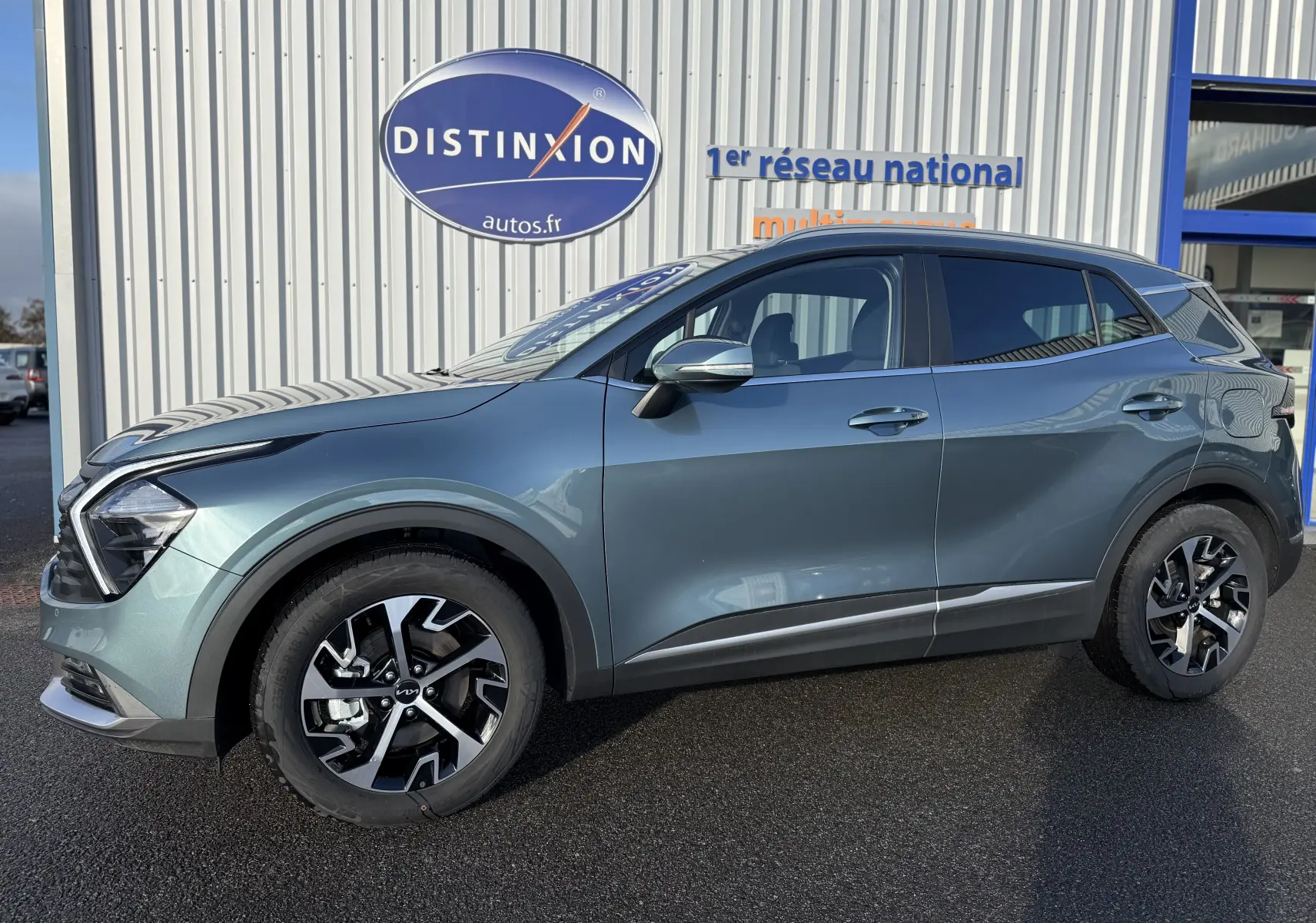Profil côté gauche du SUV KIA SPORTAGE gris Sirius 2025 avec jantes alliage bicolores et lignes modernes.