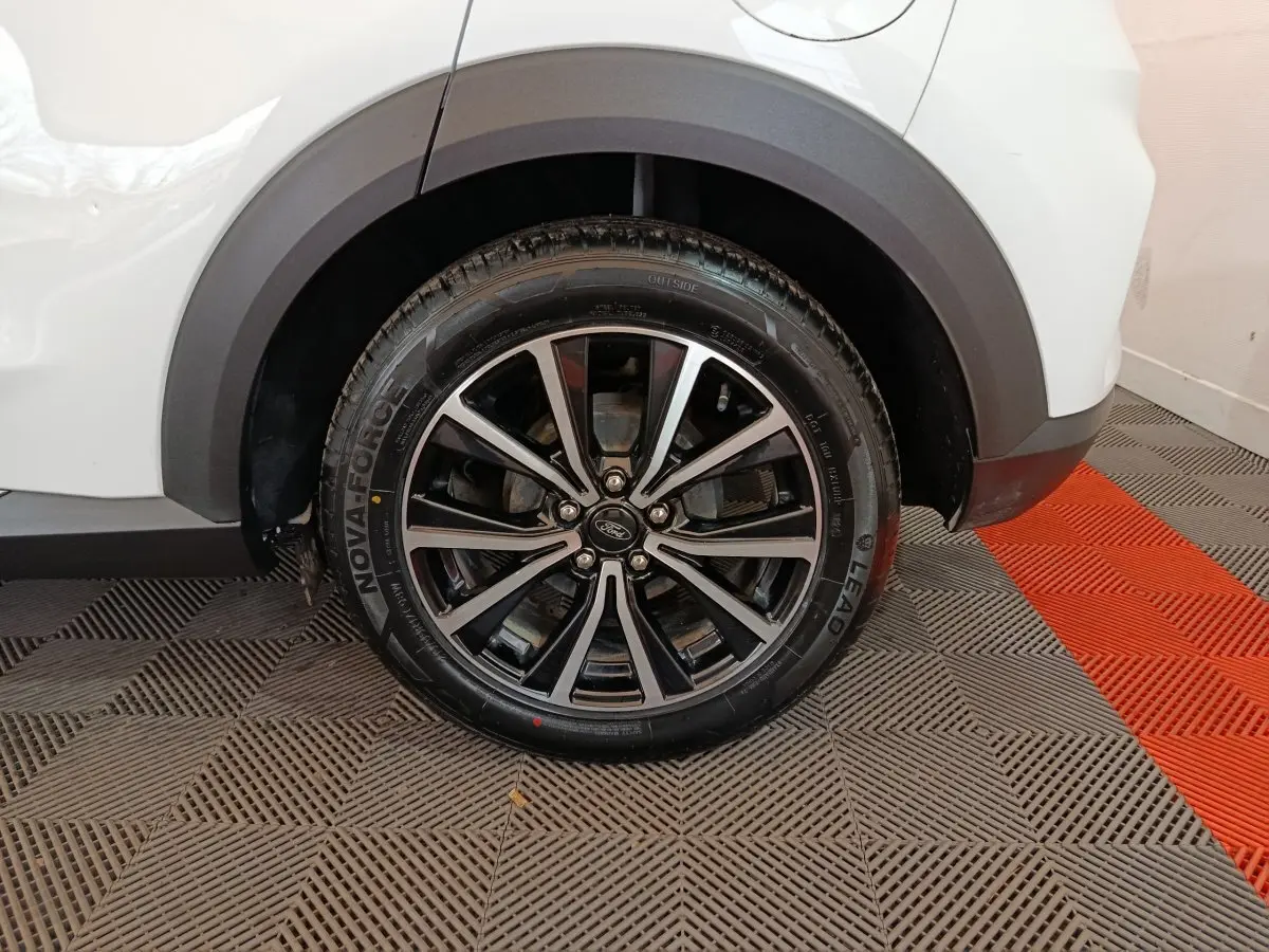 Gros plan sur la roue arrière droite avec jante alliage noir et argent du Ford Puma blanc 2022.