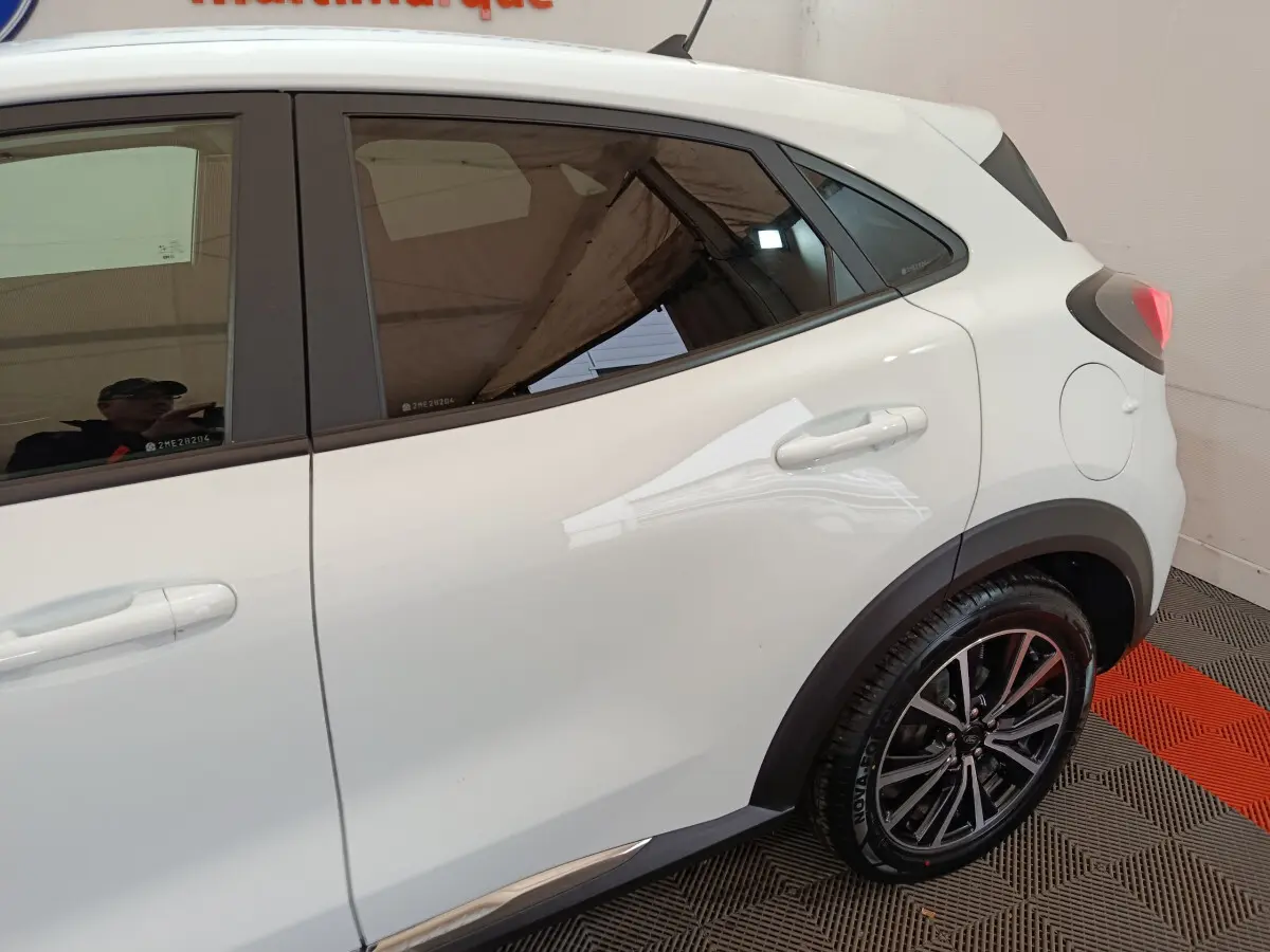 Vue côté droit arrière du Ford Puma blanc 2022 avec jantes alliage et protections noires sur les passages de roues.