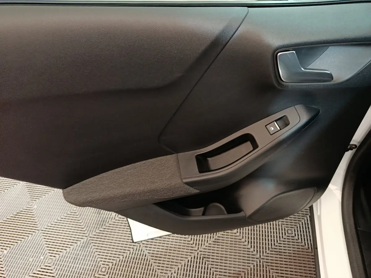 Gros plan sur la porte avant droite blanche du Ford Puma 2022, avec poignée intérieure et commandes de vitre noires.