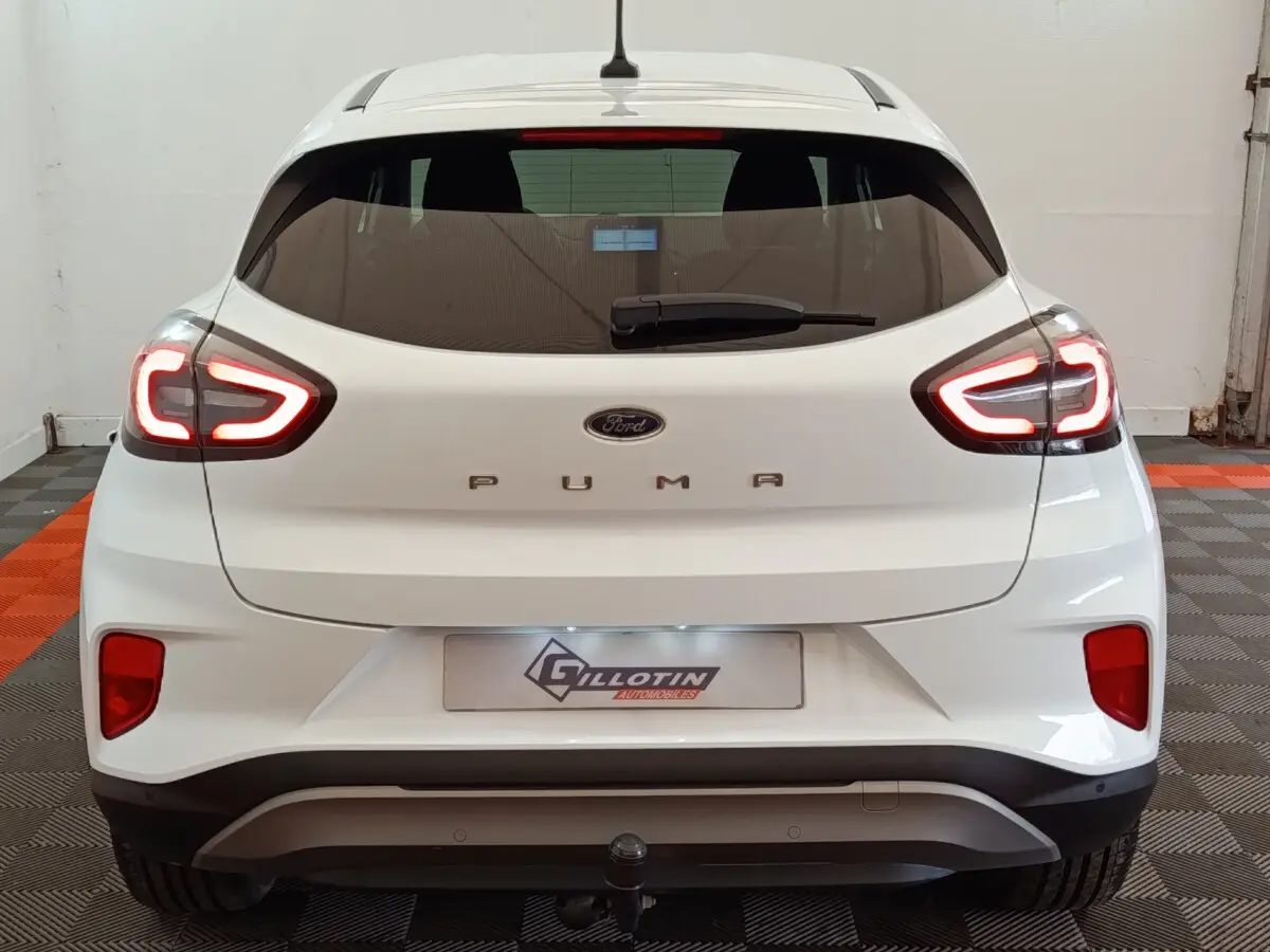 Vue arrière d'une Ford Puma blanche 2022 avec feux LED allumés et attelage visible en intérieur.