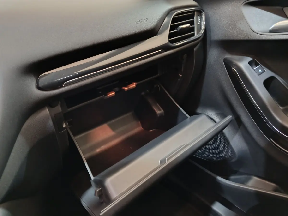 Vue intérieure côté passager du Ford Puma 2022 blanc, boîte à gants ouverte et tableau de bord noir.