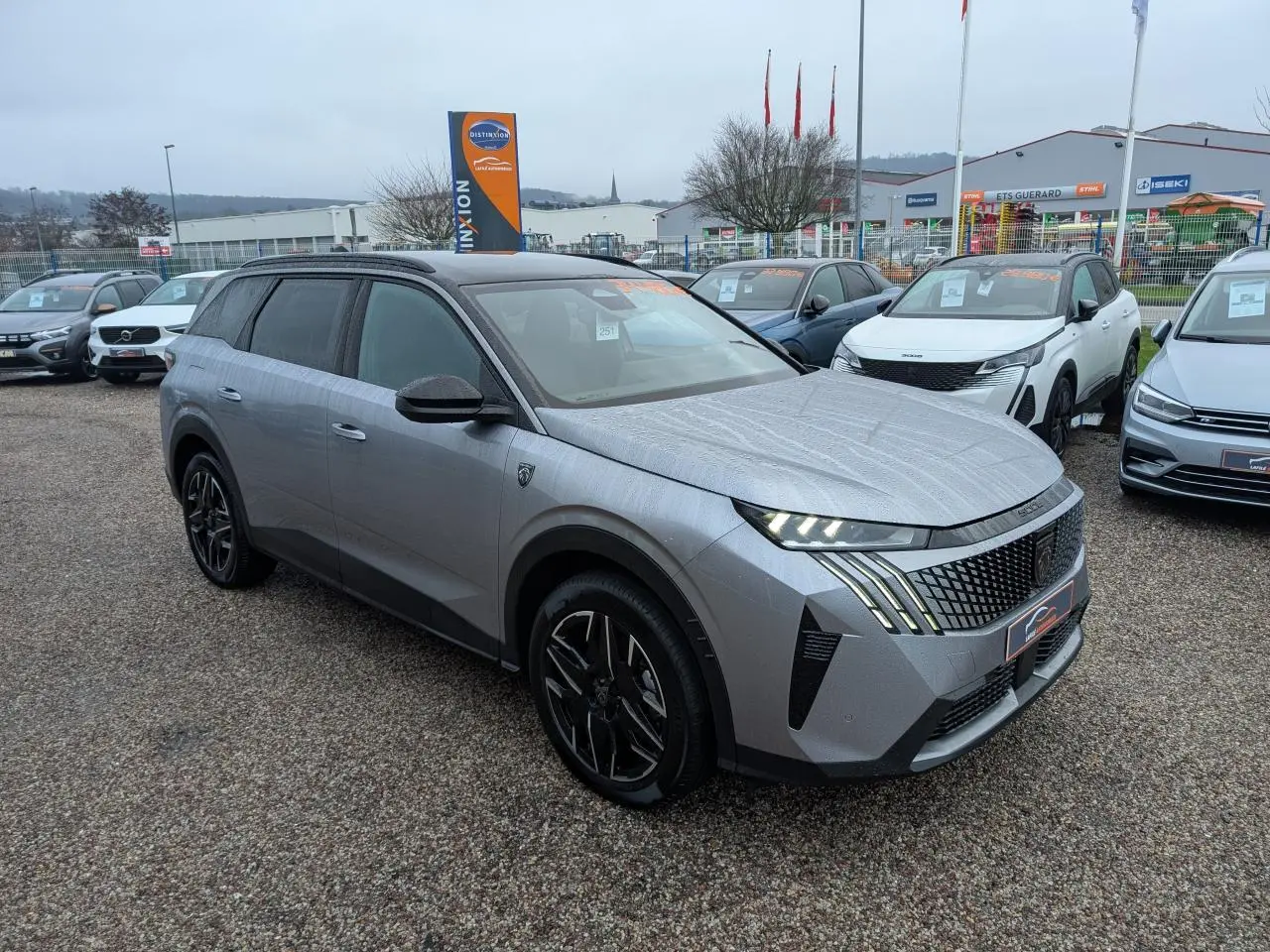 Peugeot 5008 gris métallisé vue 3/4 avant droit, avec jantes alliage noires et feux LED distinctifs.
