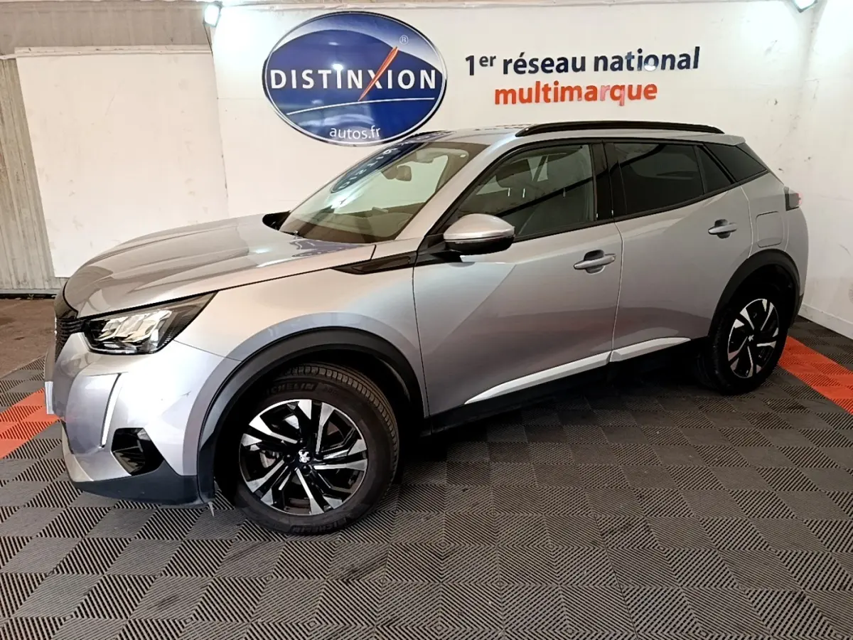 Peugeot 2008 gris clair vue de profil droit en intérieur, avec jantes noires et toit noir contrasté.