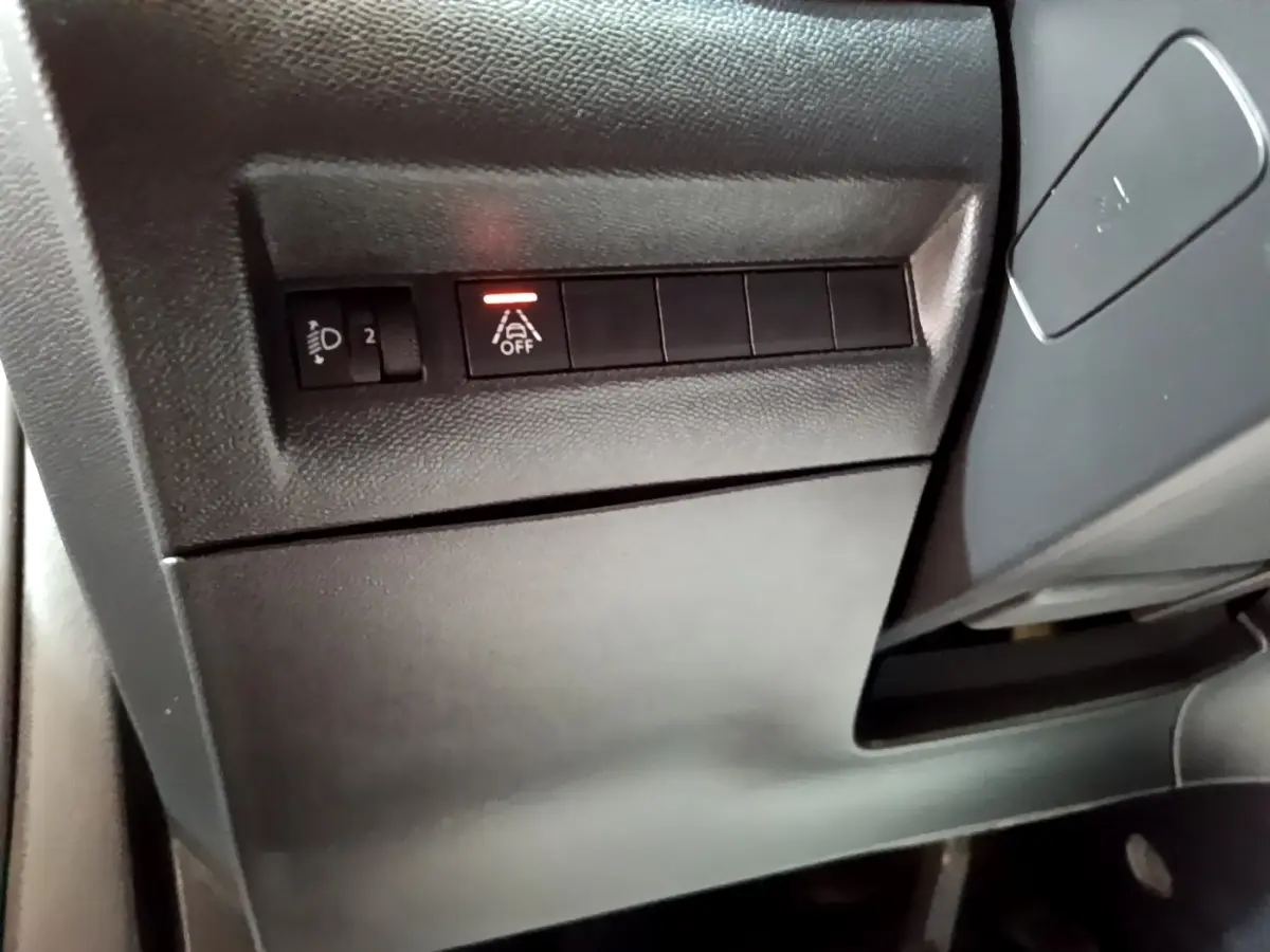 Détail intérieur montrant les commandes d'assistance à la conduite avec bouton désactivation sur Peugeot 2008 gris clair.