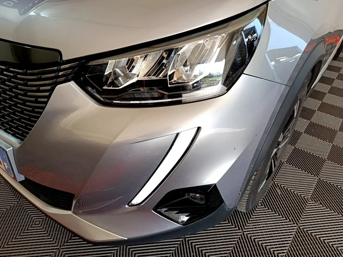 Gros plan sur l'avant droit gris clair du Peugeot 2008 2021 avec phares LED et feux diurnes en forme de griffes.