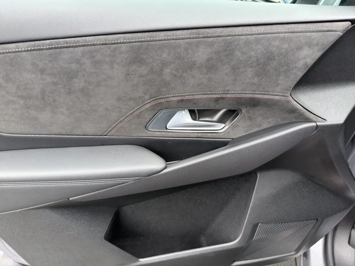 Gros plan sur la porte intérieure côté droit du DS7 Crossback gris clair, avec garniture en alcantara et poignée métal.