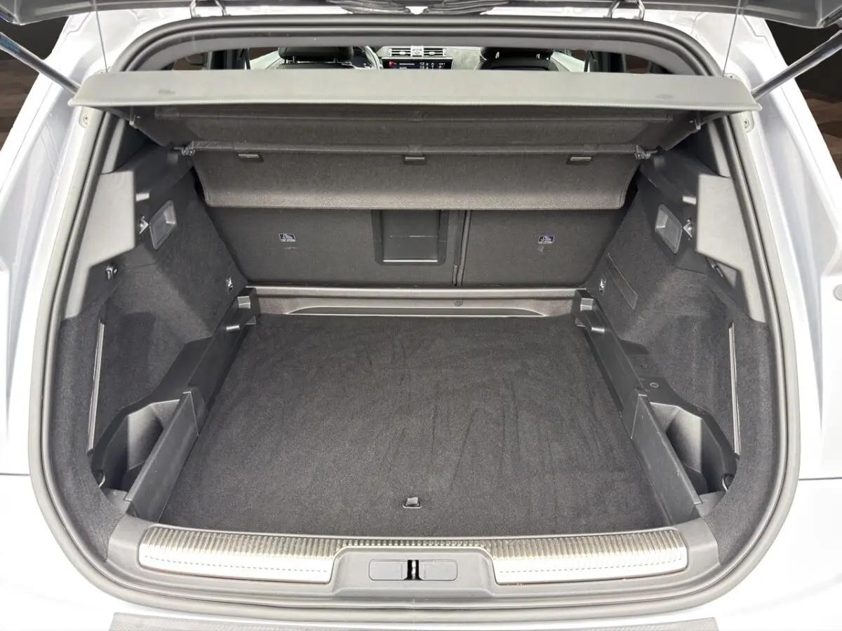 Coffre ouvert vu de l'arrière d'un DS7 Crossback gris clair, montrant un espace de chargement propre et bien agencé.