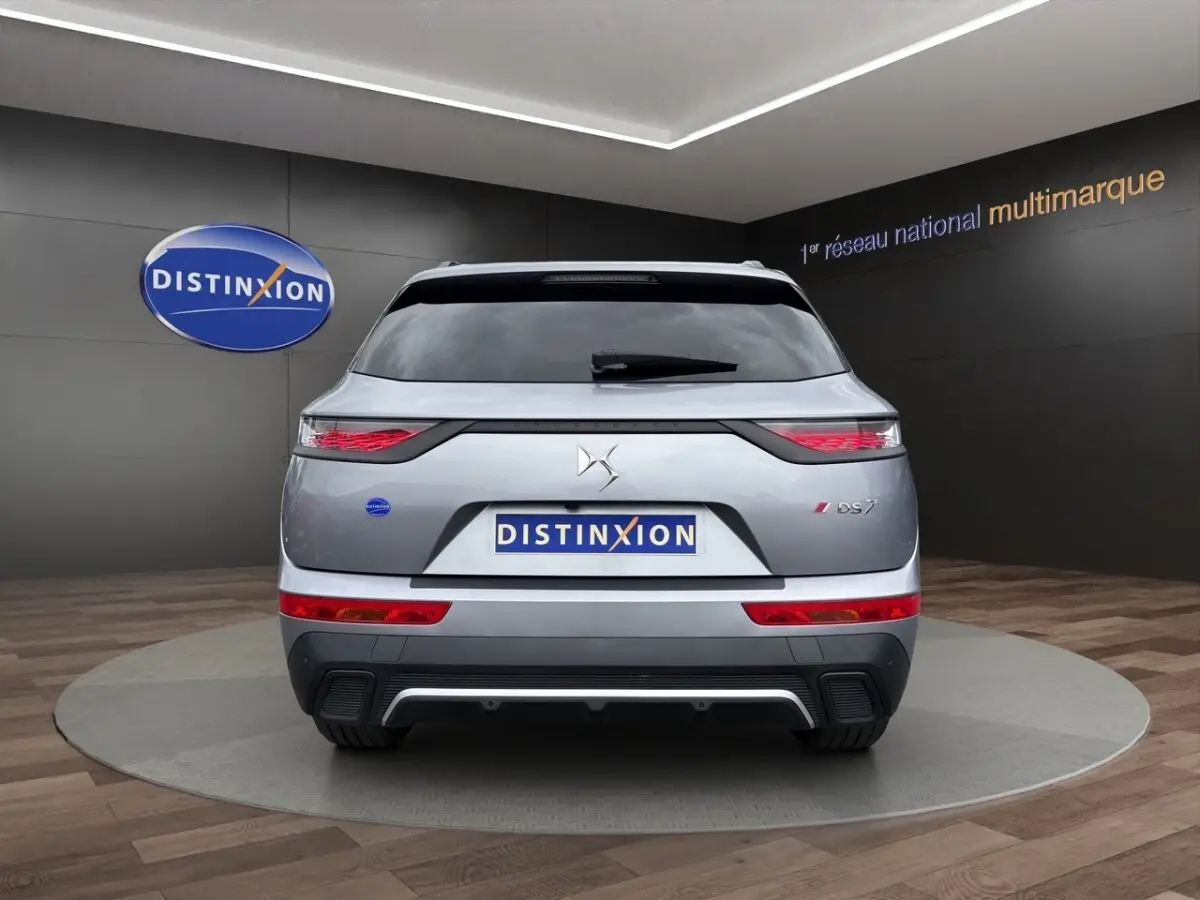 Vue arrière d'un DS7 Crossback gris clair avec feux LED et logo DS bien visibles sur fond intérieur showroom.
