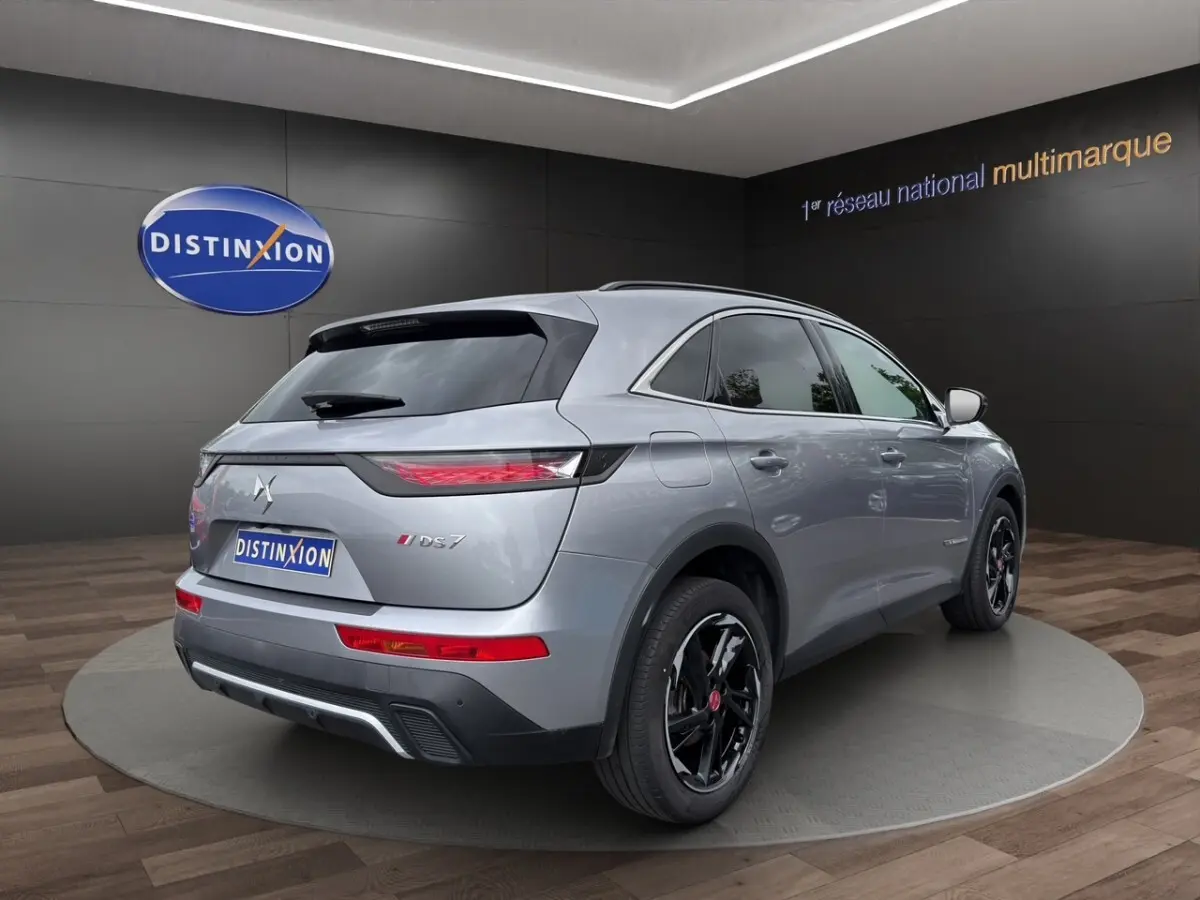Vue 3/4 arrière droite d’un DS7 Crossback gris clair avec jantes noires et feux arrière LED distinctifs.