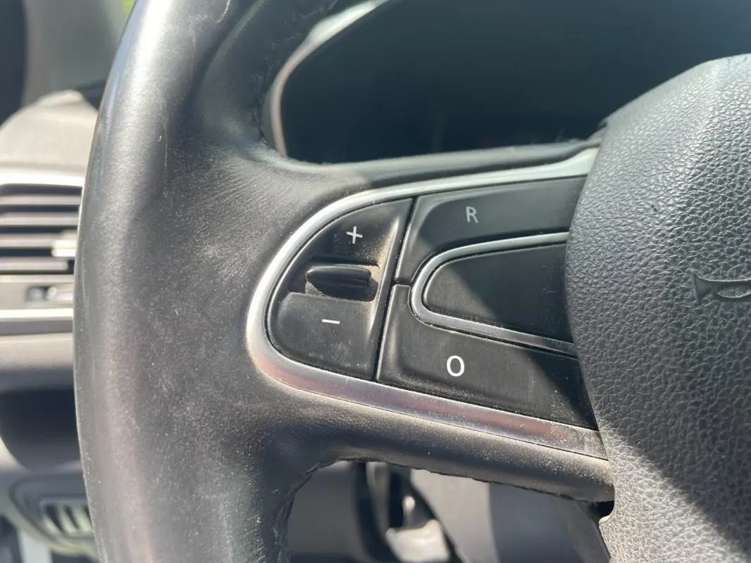 Gros plan sur les commandes de régulateur de vitesse au volant noir de la Renault Mégane IV Berline 2016.