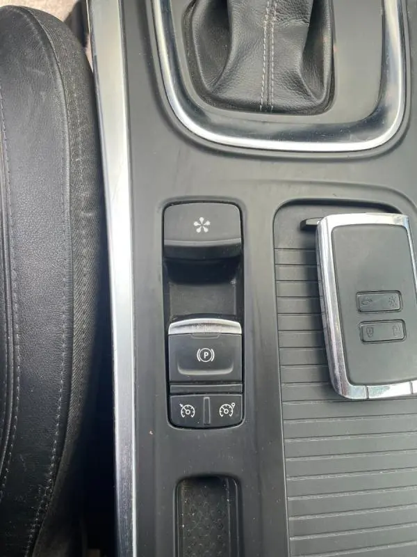 Gros plan sur la console centrale noire de la Renault Mégane IV blanche, montrant les commandes électroniques et la clé.