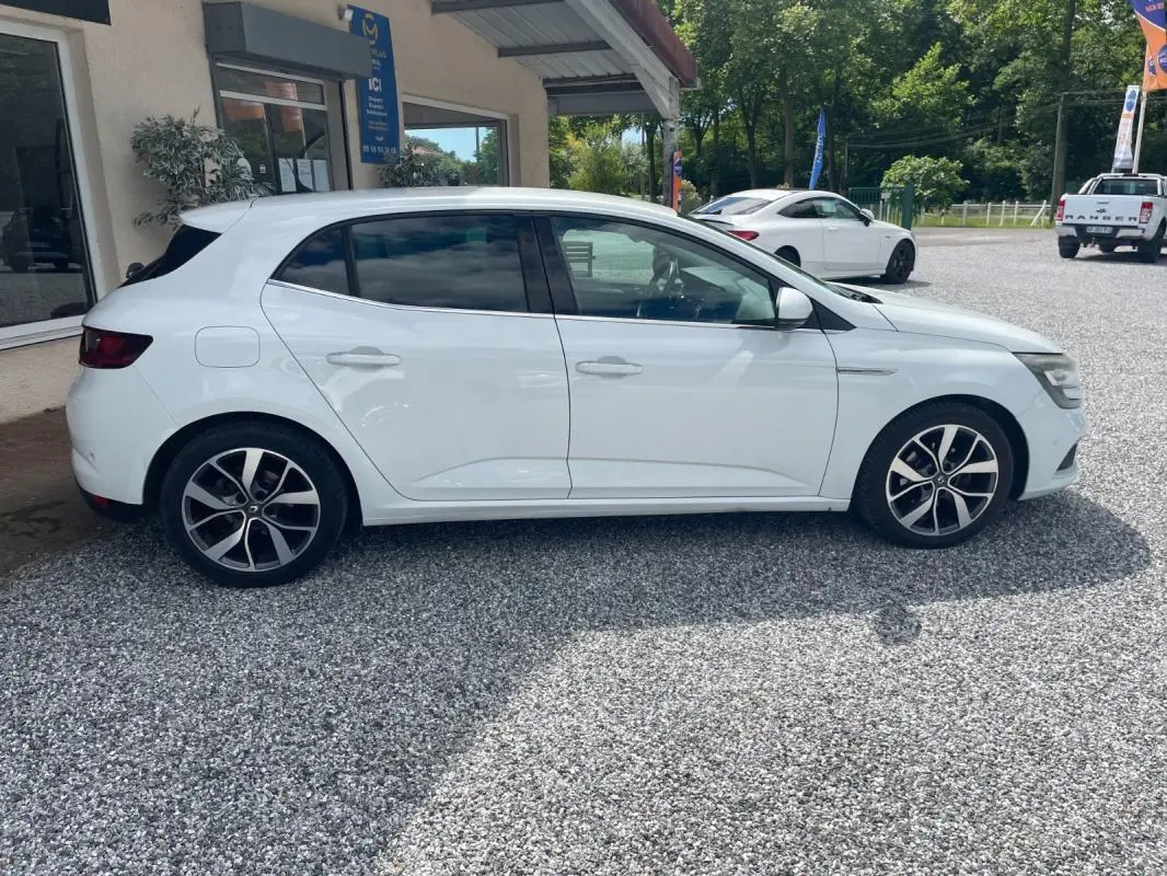 Renault Mégane IV blanche vue de profil côté gauche, avec jantes alliage distinctives et vitres teintées.