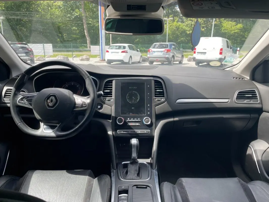 Vue intérieure frontale du tableau de bord et volant noir de la Renault Mégane IV Berline 2016, avec écran tactile central.