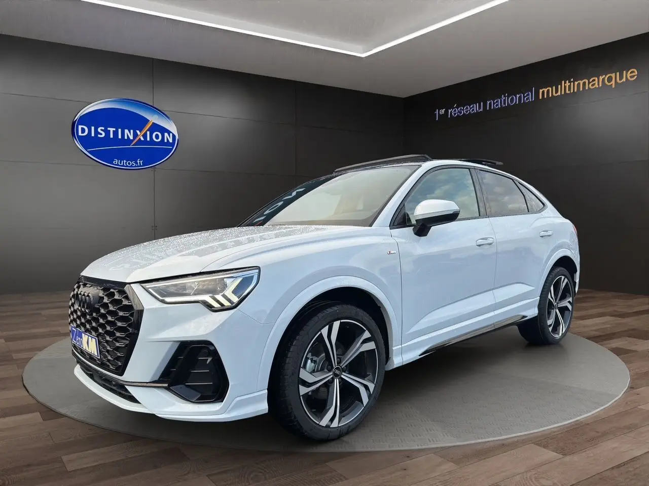 Audi Q3 Sportback blanc glacier en 3/4 avant droit, avec jantes sport noires et toit panoramique visible.