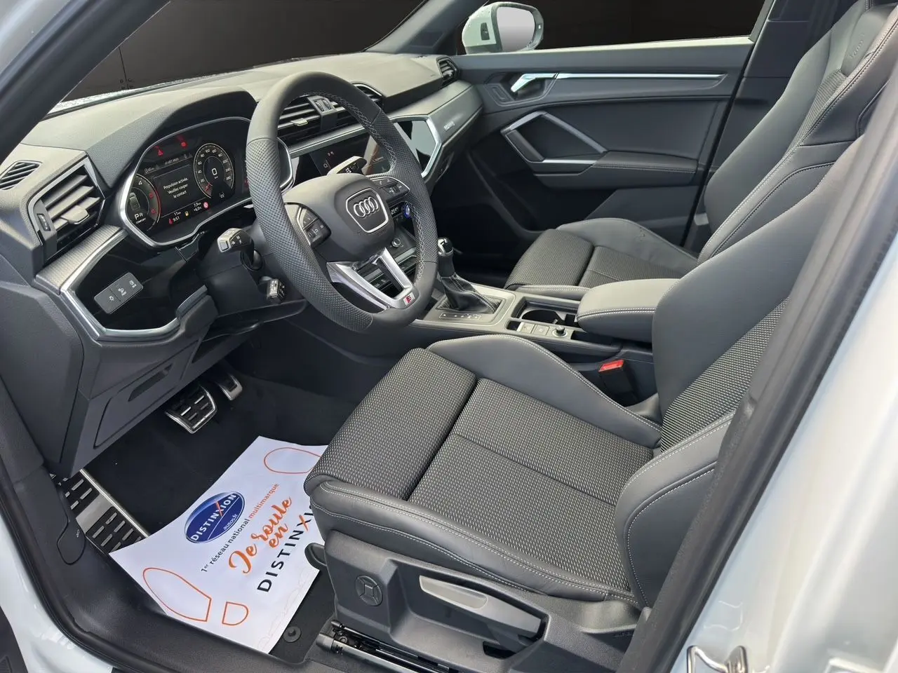 Intérieur noir de l'Audi Q3 Sportback S line 2024 vu côté conducteur avec volant multifonction et sièges sport.