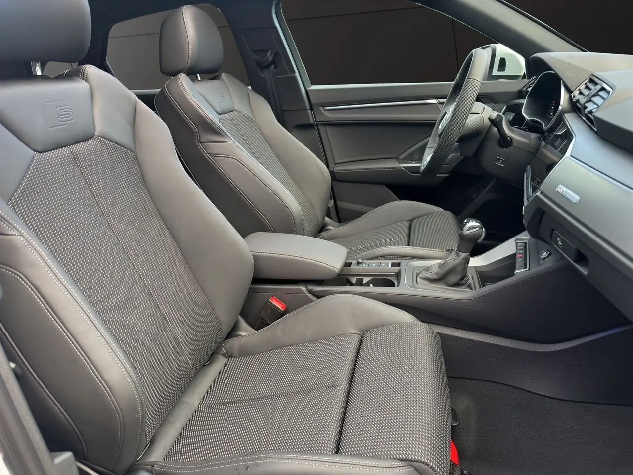 Intérieur avant de l'Audi Q3 Sportback S Line 2024 avec sièges sport noirs et console centrale moderne.