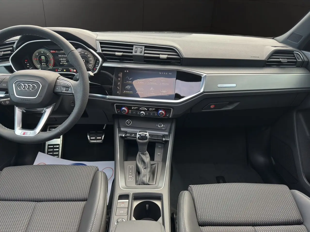 Vue intérieure avant de l'Audi Q3 Sportback S line 2024 avec tableau de bord noir et console centrale moderne.