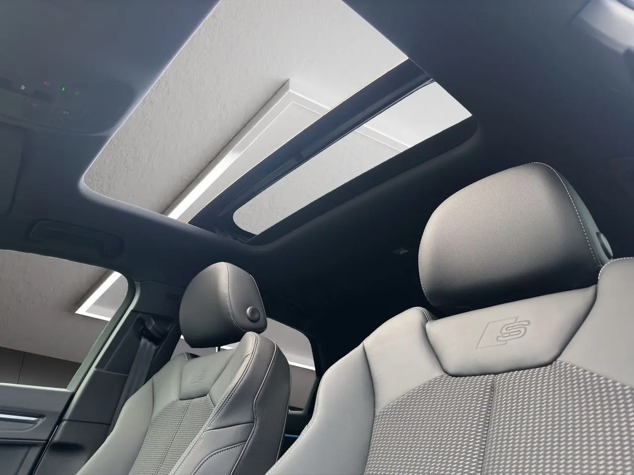 Intérieur noir de l'Audi Q3 Sportback S line 2024, sièges sport avec logo S et toit panoramique ouvert.