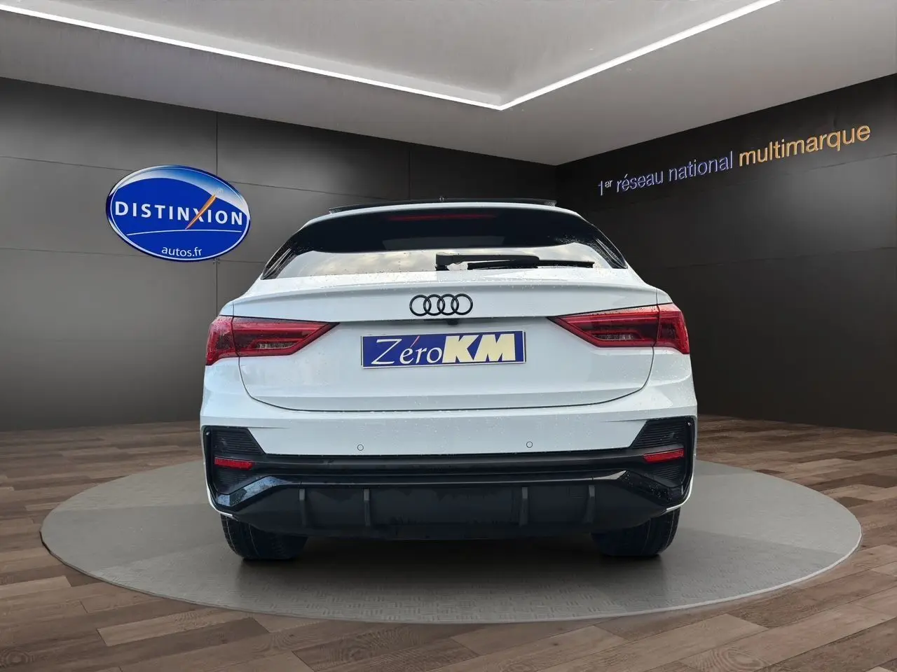 Vue arrière d'un Audi Q3 Sportback blanc Glacier avec pare-chocs S line et feux arrière LED dans un showroom