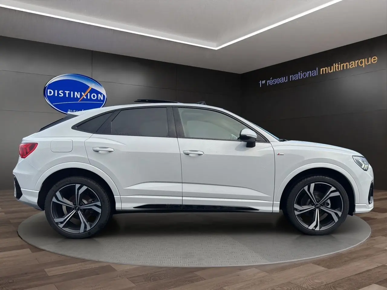 Audi Q3 Sportback blanc vue profil côté gauche avec jantes noires sport à 5 branches doubles en showroom