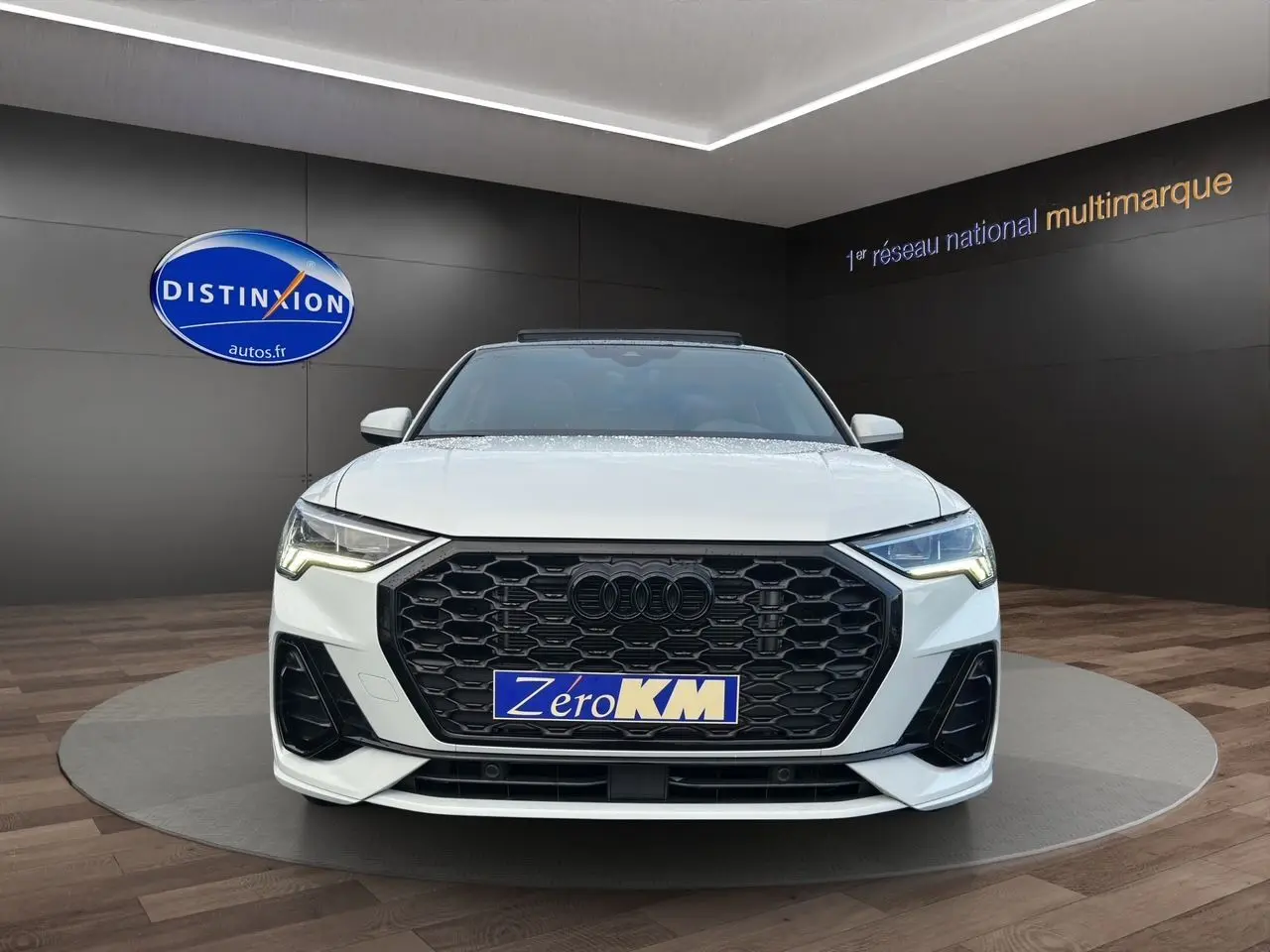 Audi Q3 Sportback blanc vue de face avec calandre noire hexagonale et phares LED allumés